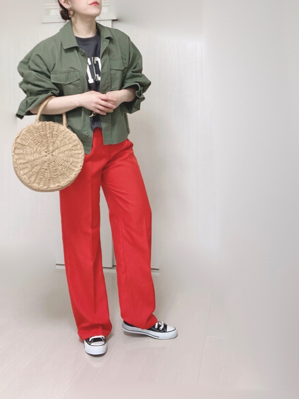 ベージュ系のかごバッグ、グリーン系のミリタリージャケット、ブラック系のスニーカーを着用したレディースの春コーディネートの3枚目の写真