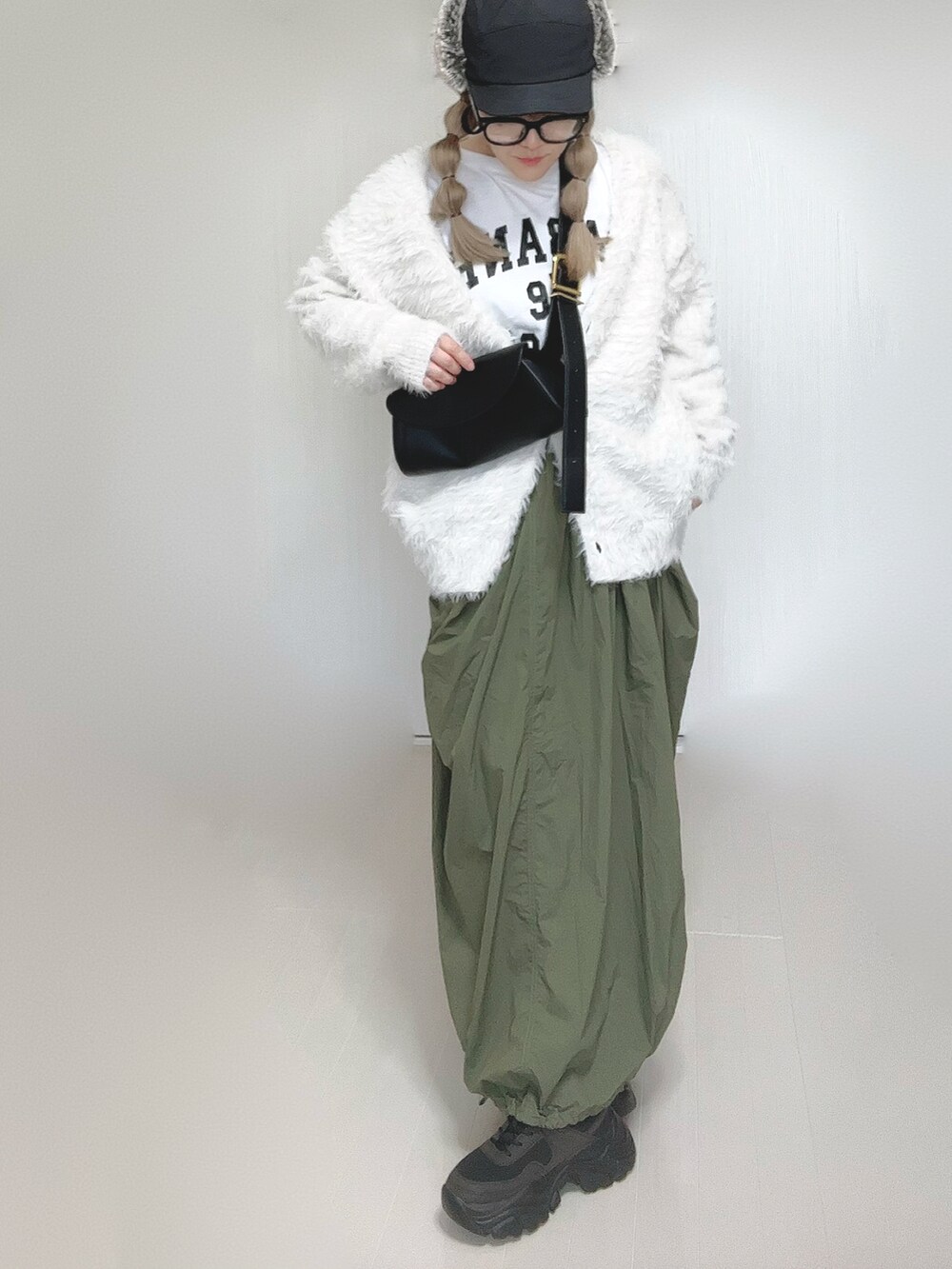ホワイト系のカーディガン/ボレロ、ホワイト系のTシャツ/カットソー、グリーン系のスカートを着用したレディースの秋コーディネートの5枚目の写真