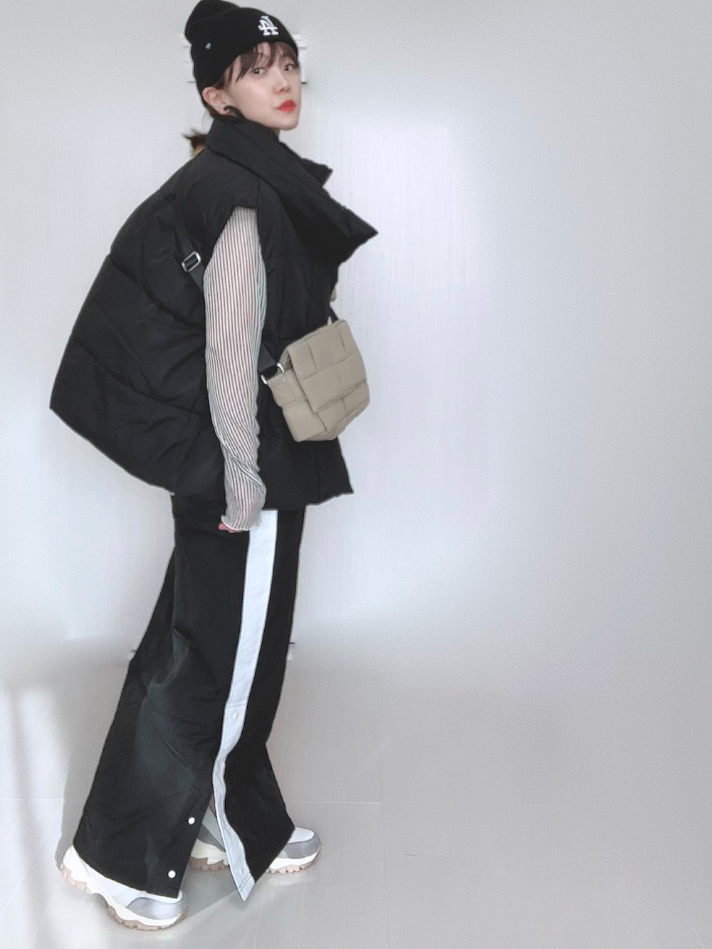 ブラック系のスカート、ブラック系のダウンベスト、ホワイト系のシャツ/ブラウスを着用したレディースの冬コーディネートの2枚目の写真