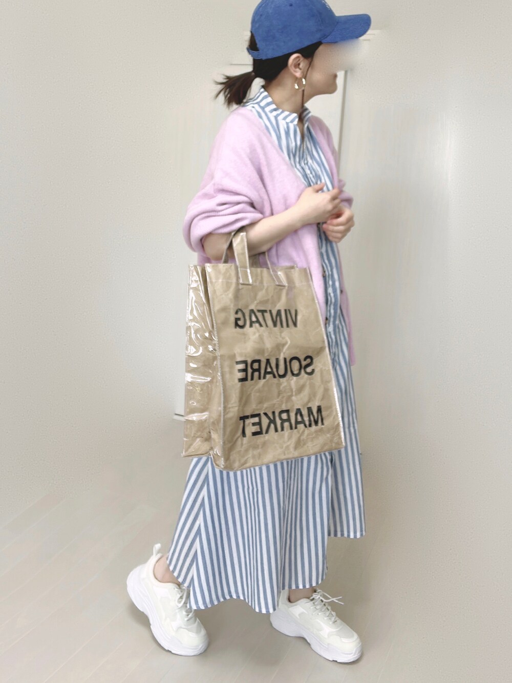 ブルー系のシャツワンピース、パープル系のカーディガン/ボレロ、グリーン系のトートバッグを着用したレディースの春コーディネートの2枚目の写真