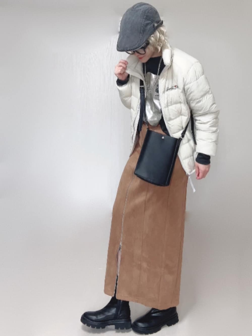 ブラック系のブーツ、ホワイト系のダウンジャケット/コート、ブラック系のショルダーバッグを着用したレディースの秋コーディネートの2枚目の写真