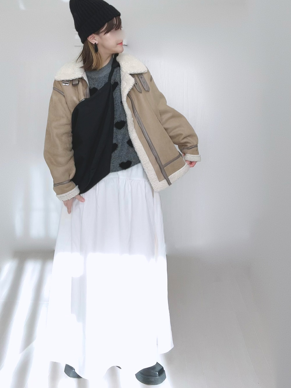 ベージュ系のムートンコート、ホワイト系のスカート、ブラック系のブーツを着用したレディースの冬コーディネートの3枚目の写真