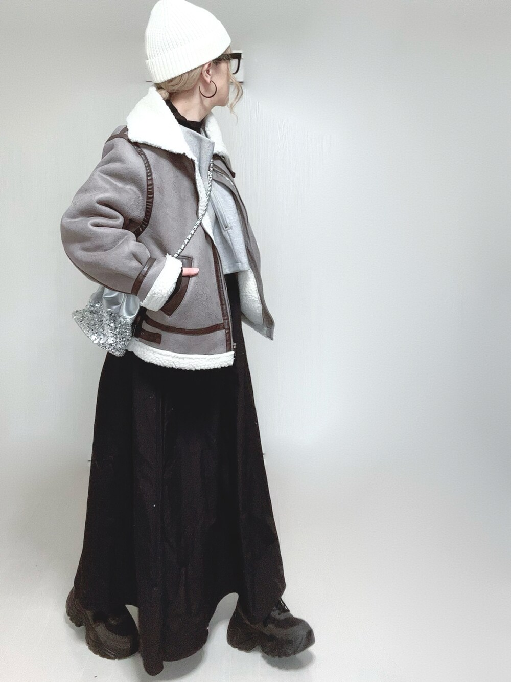 グレー系のムートンコート、グレー系のワンピース、シルバー系のショルダーバッグを着用したレディースの冬コーディネートの2枚目の写真