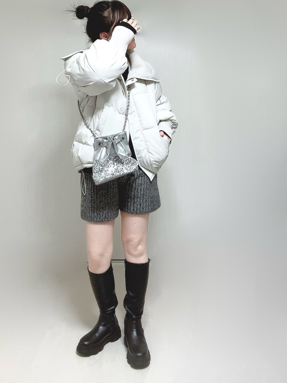 ホワイト系のダウンジャケット/コート、ブラック系のニット/セーター、ブラック系のブーツを着用したレディースの冬コーディネートの4枚目の写真