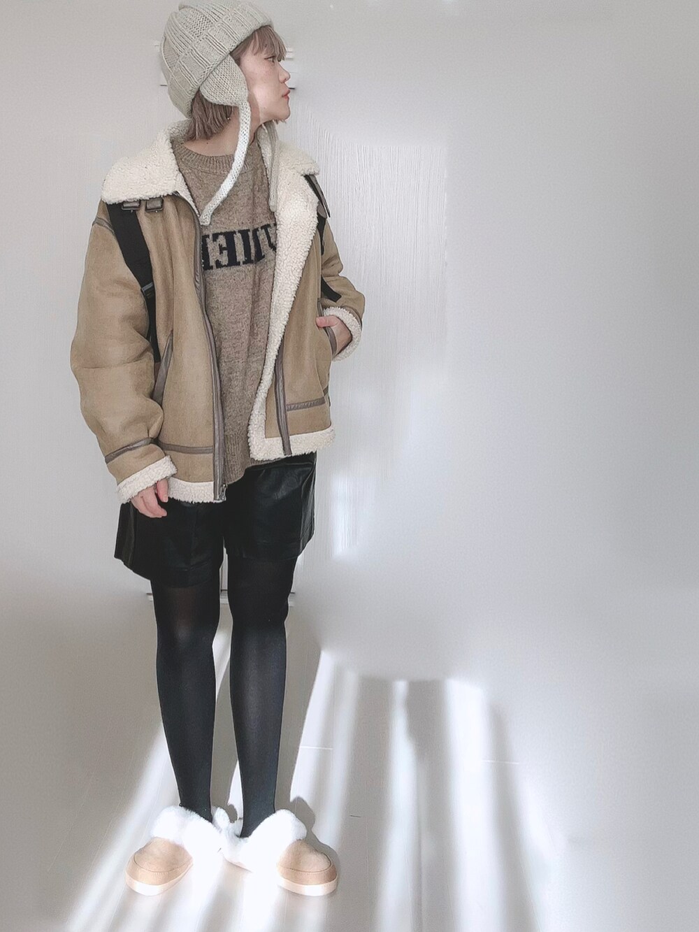 ベージュ系のムートンコート、ベージュ系のニット/セーター、ブラック系のバックパック/リュックを着用したレディースの冬コーディネートの4枚目の写真