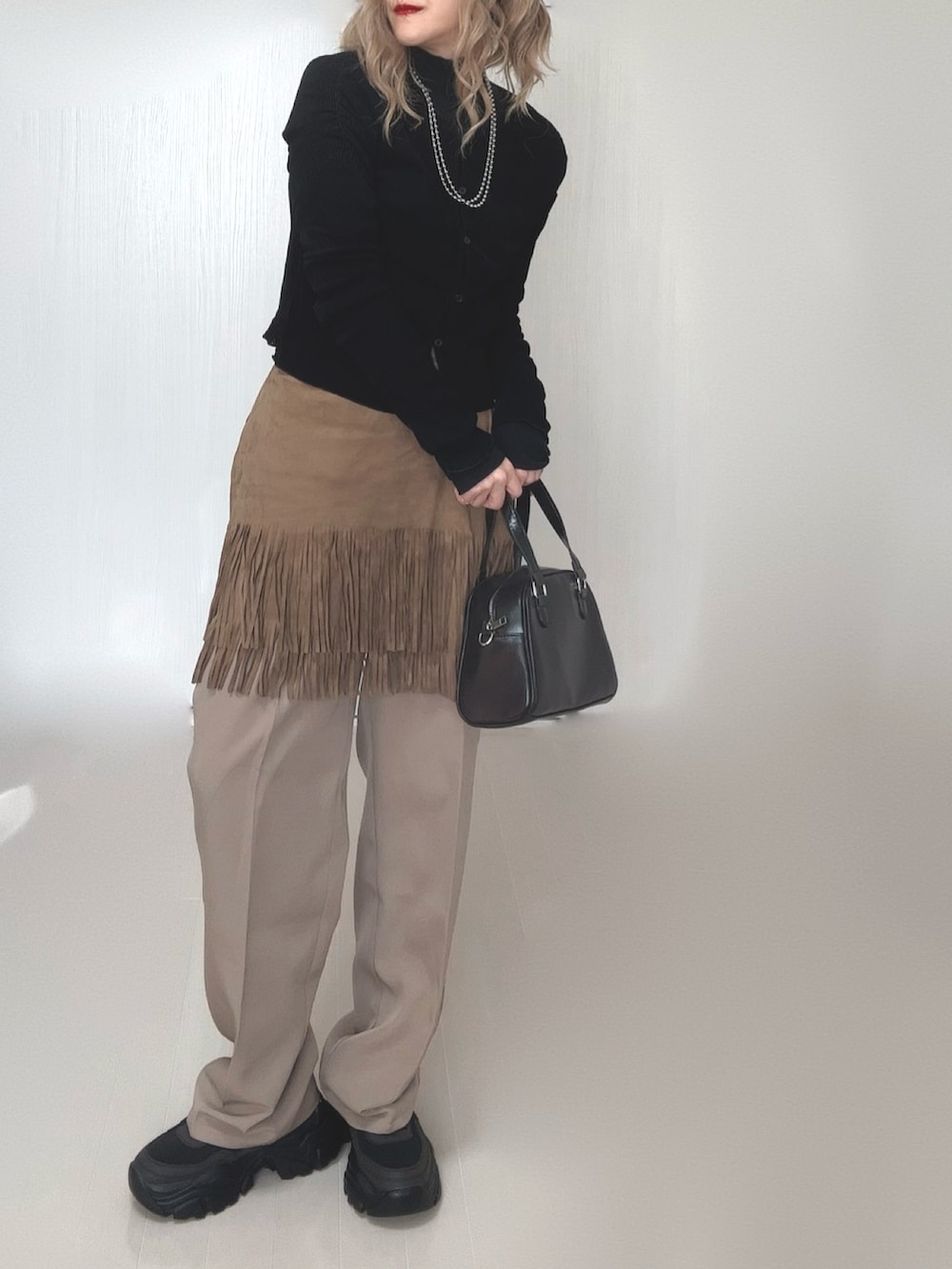 ブラック系のカーディガン/ボレロ、ブラック系のTシャツ/カットソー、ベージュ系のスカートを着用したレディースの冬コーディネートの4枚目の写真