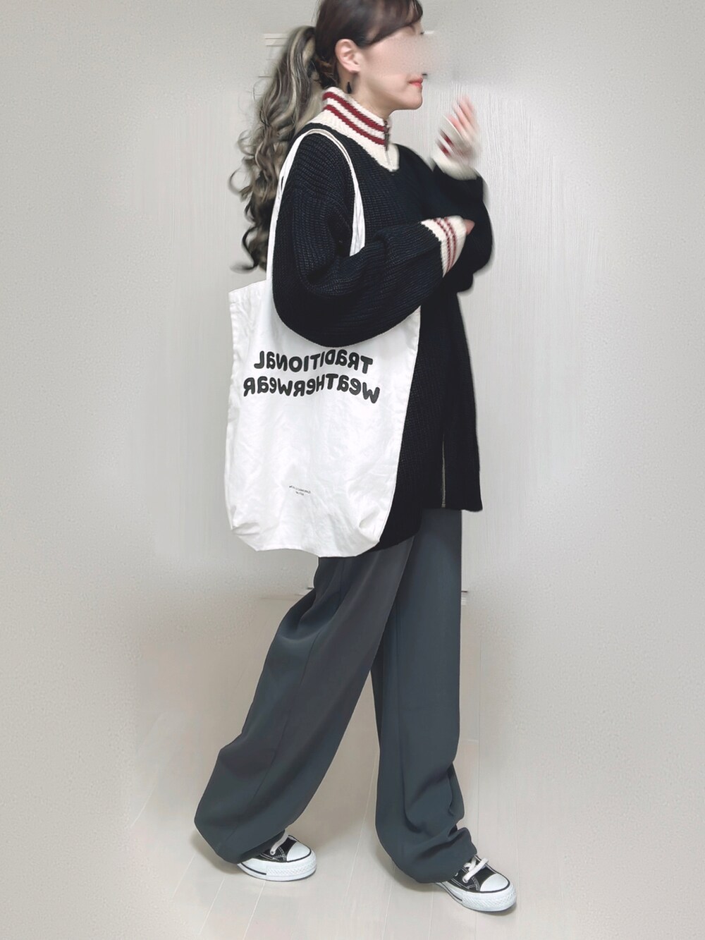 ブラック系のニット/セーター、ホワイト系のトートバッグ、グレー系のスラックスを着用したレディースの秋コーディネートの2枚目の写真