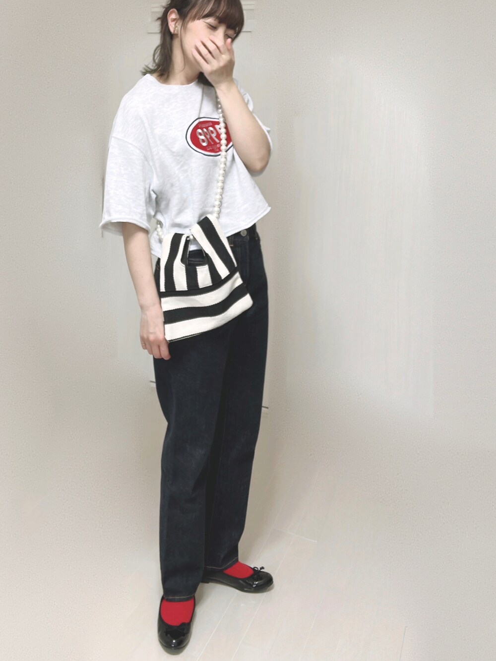 ホワイト系のショルダーバッグ、ブルー系のデニムパンツ、ブラック系のバレエシューズを着用したレディースの夏コーディネートの2枚目の写真