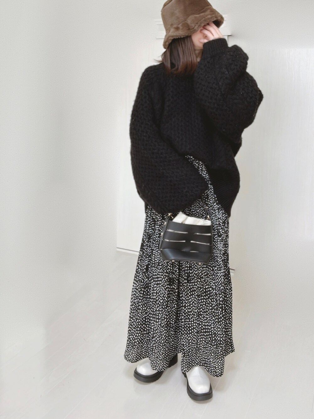 ブラック系のニット/セーター、ブラック系のショルダーバッグ、ブラック系のスカートを着用したレディースの冬コーディネートの5枚目の写真