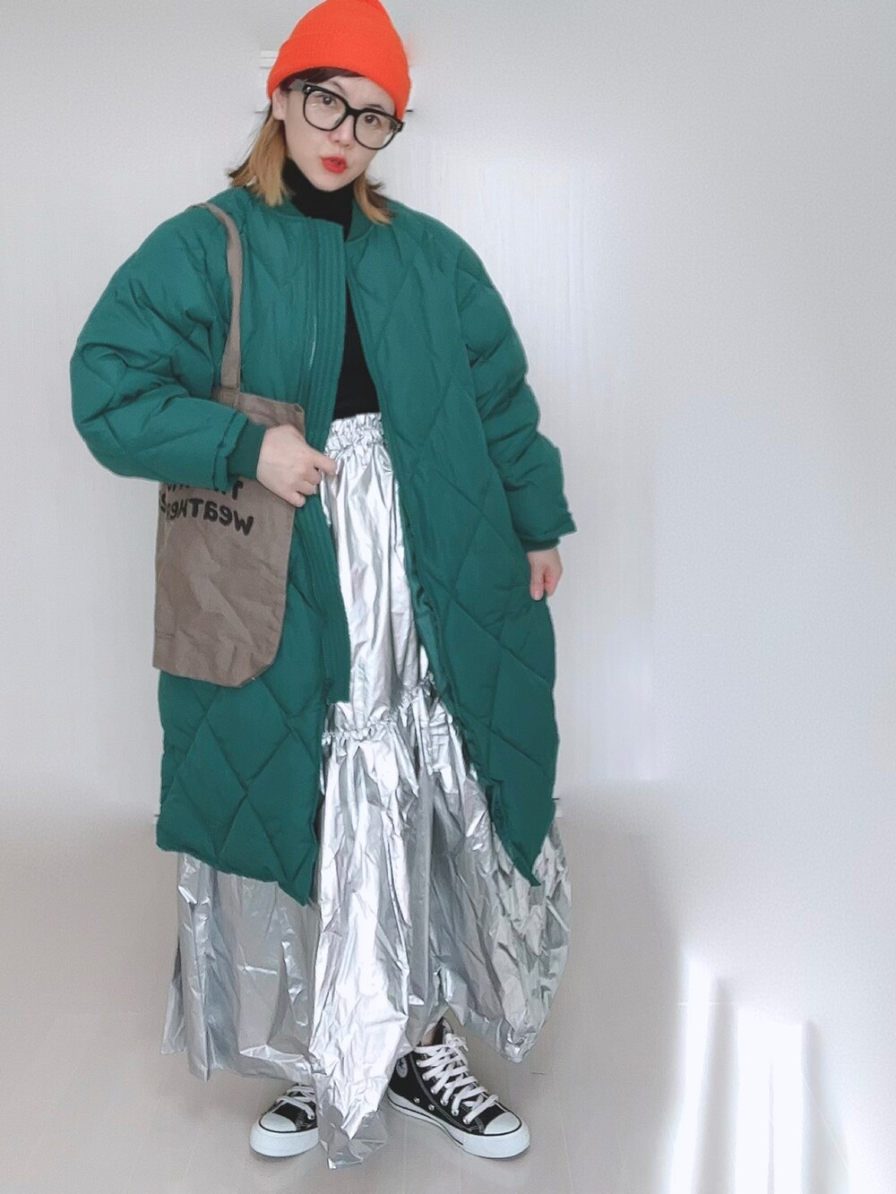 グリーン系のダウンジャケット/コート、ブラウン系のトートバッグ、シルバー系のスカートを着用したレディースの冬コーディネートの5枚目の写真