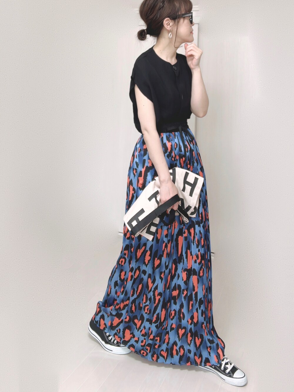 ブルー系のスカート、ブラック系のベスト、ホワイト系のトートバッグを着用したレディースの夏コーディネートの3枚目の写真