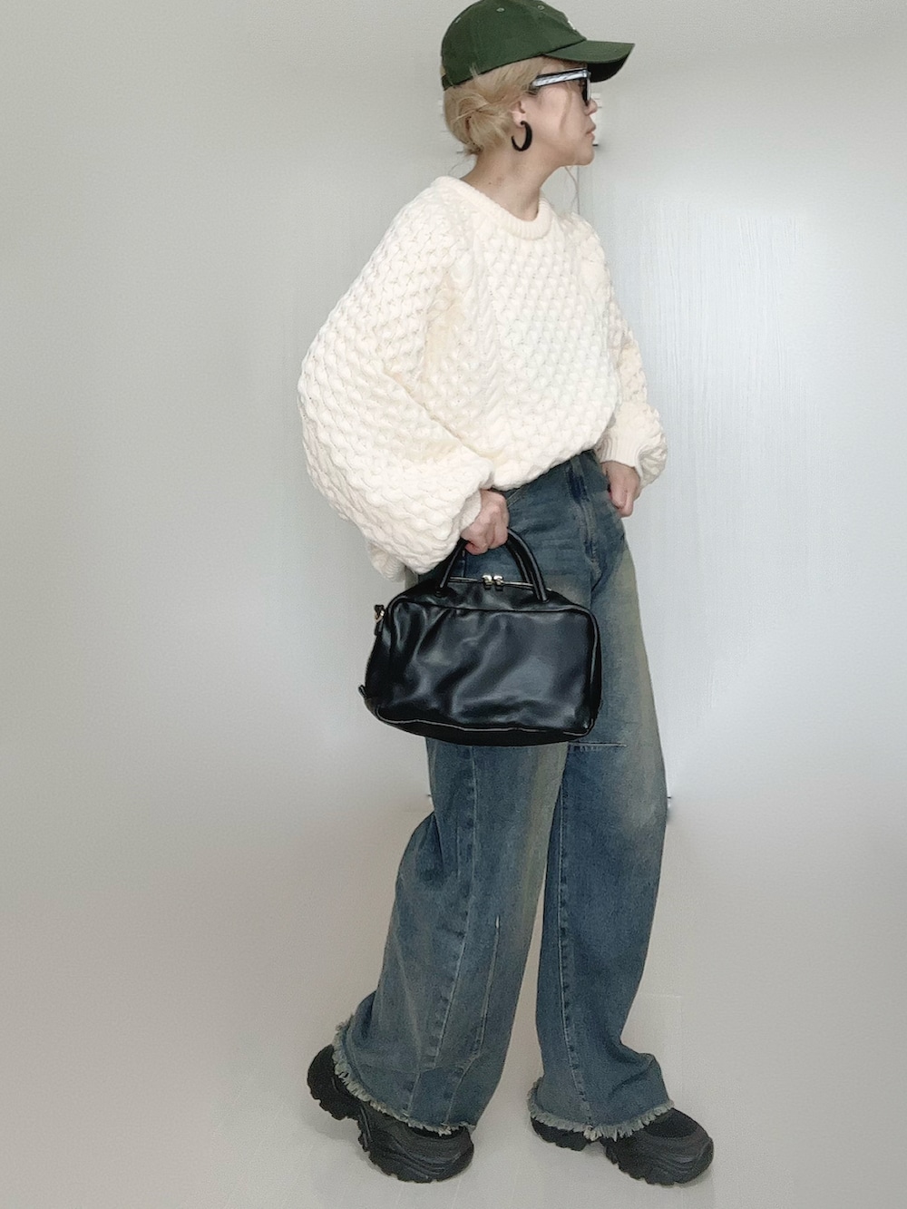 ブルー系のデニムパンツ、ホワイト系のニット/セーター、ブラック系のボストンバッグを着用したレディースの秋コーディネートの4枚目の写真