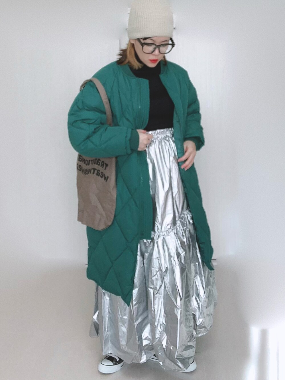 グリーン系のダウンジャケット/コート、ブラウン系のトートバッグ、シルバー系のスカートを着用したレディースの冬コーディネートの2枚目の写真