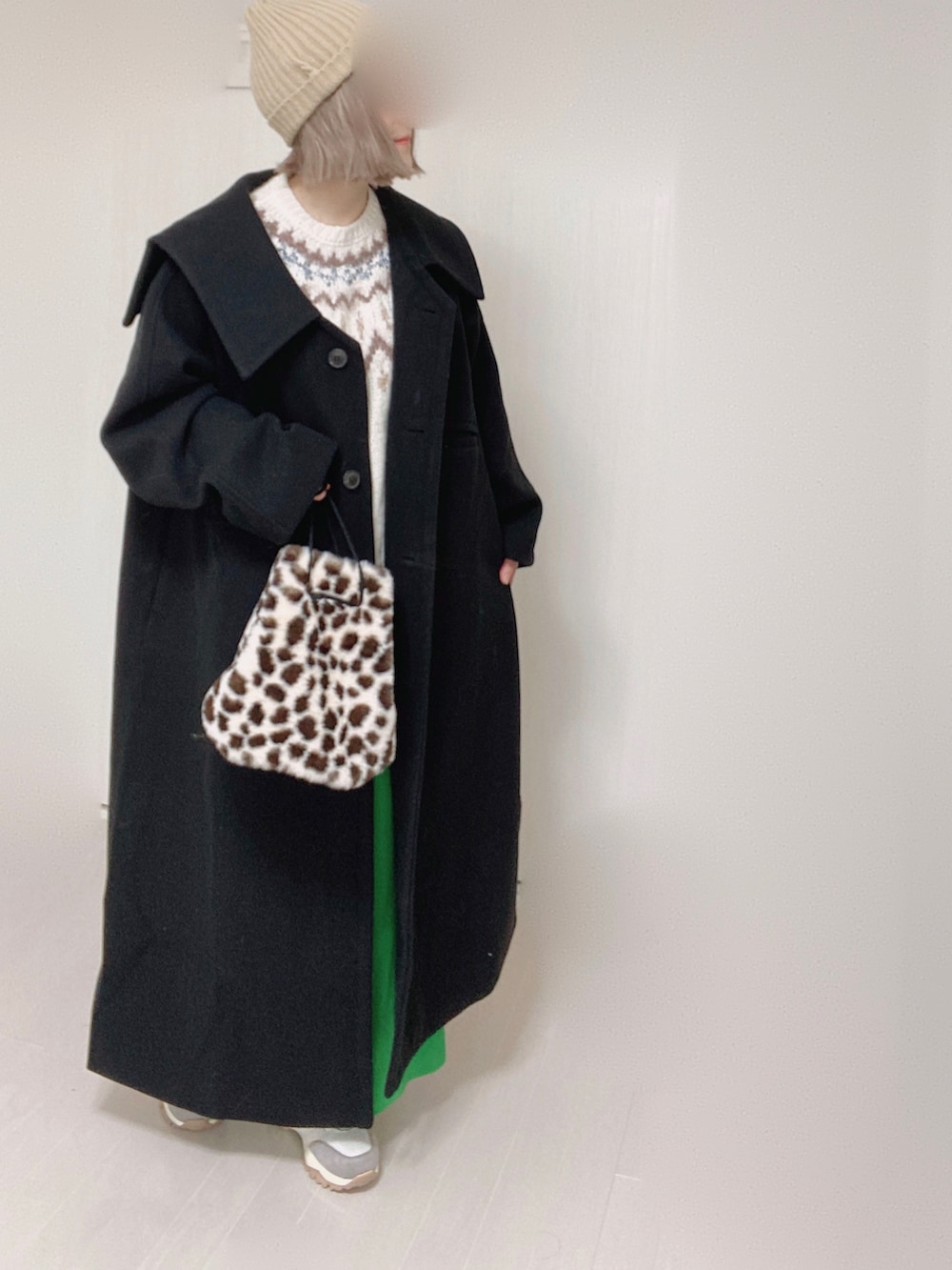 ベージュ系のスニーカー、ブラック系のステンカラーコート、ホワイト系のニット/セーターを着用したレディースの秋コーディネートの3枚目の写真