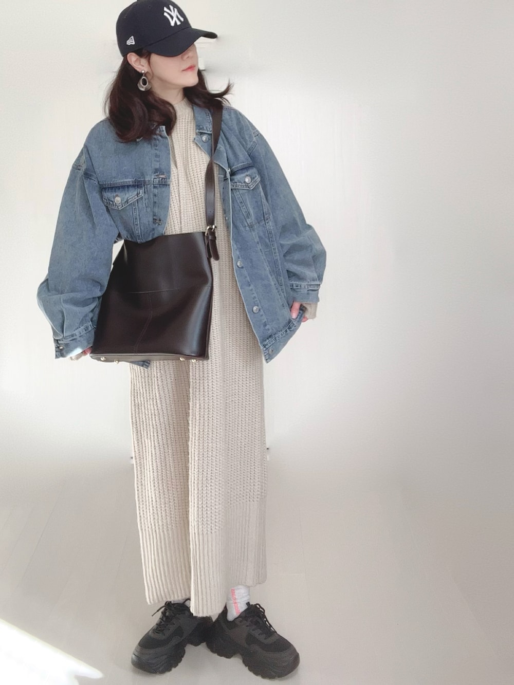 ブルー系のデニムジャケット、ホワイト系のワンピース、ブラック系のスニーカーを着用したレディースの冬コーディネートの4枚目の写真