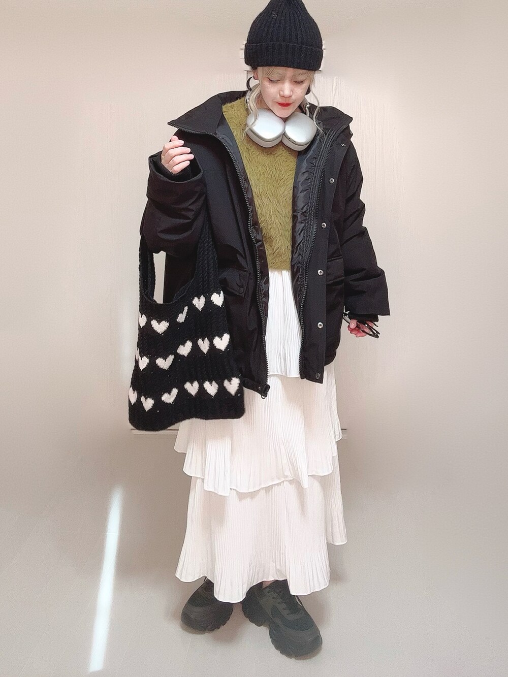 ブラック系のブルゾン、グリーン系のニット/セーター、ホワイト系のスカートを着用したレディースの冬コーディネートの2枚目の写真