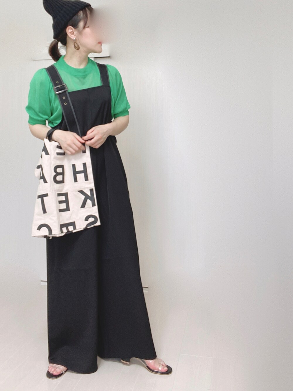 ブラック系のサロペット/オーバーオール、グリーン系のニット/セーター、ホワイト系のトートバッグを着用したレディースの夏コーディネートの5枚目の写真