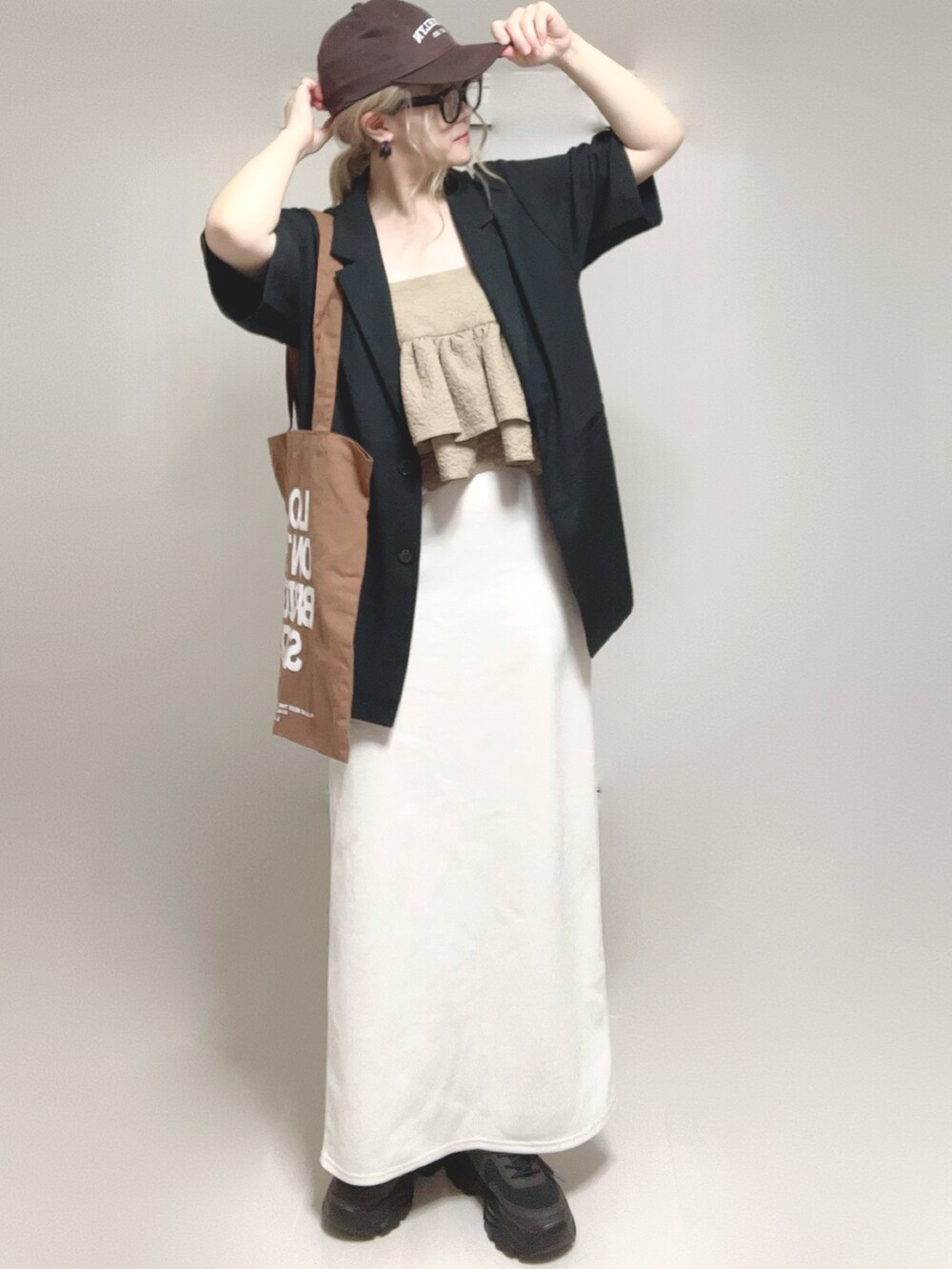 ブラック系のテーラードジャケット、ベージュ系のキャミソール、ブラック系のスニーカーを着用したレディースの夏コーディネートの3枚目の写真