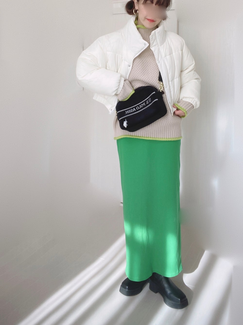 ブラック系のショルダーバッグ、ホワイト系のダウンジャケット/コート、ベージュ系のニット/セーターを着用したレディースの冬コーディネートの2枚目の写真