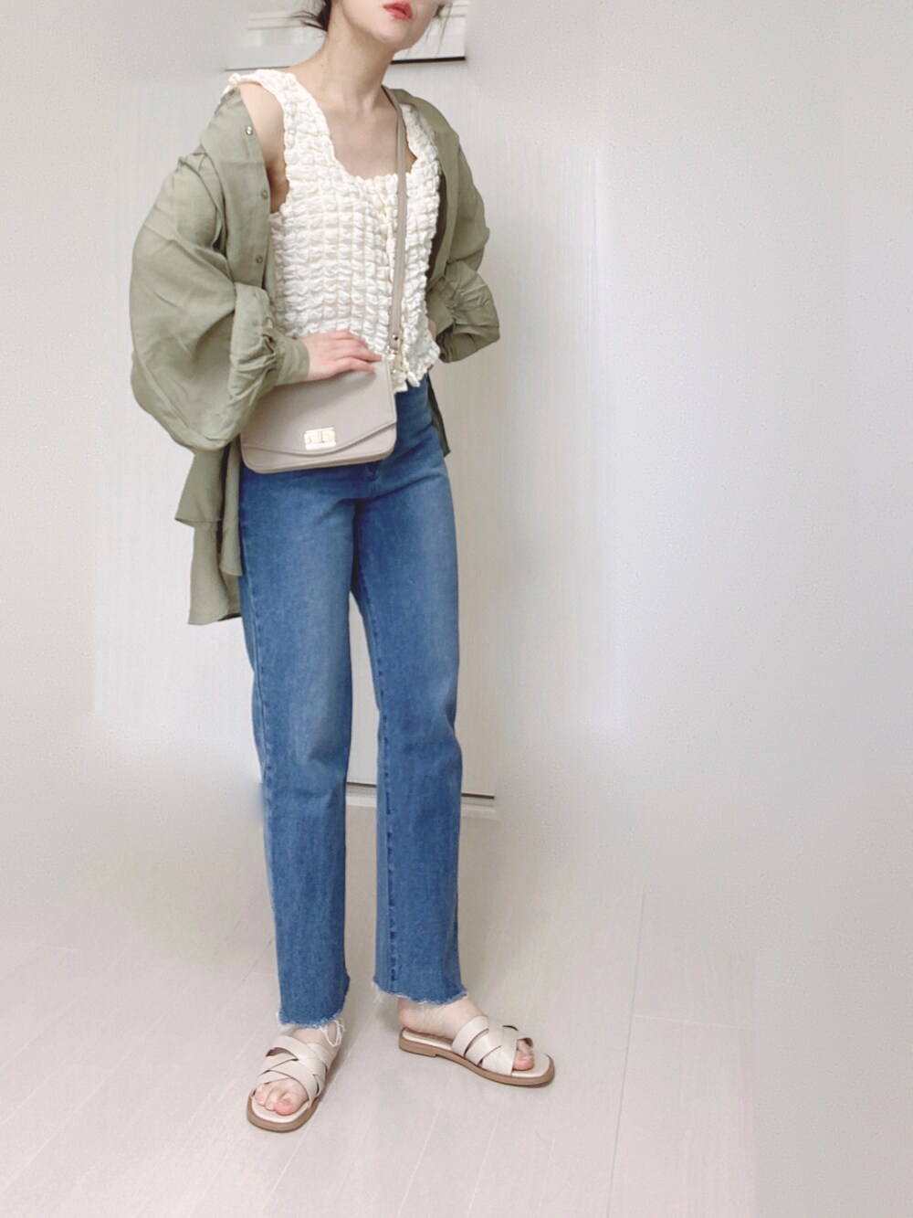 ホワイト系のサンダル、グリーン系のシャツ/ブラウス、ブルー系のデニムパンツを着用したレディースの春コーディネートの2枚目の写真