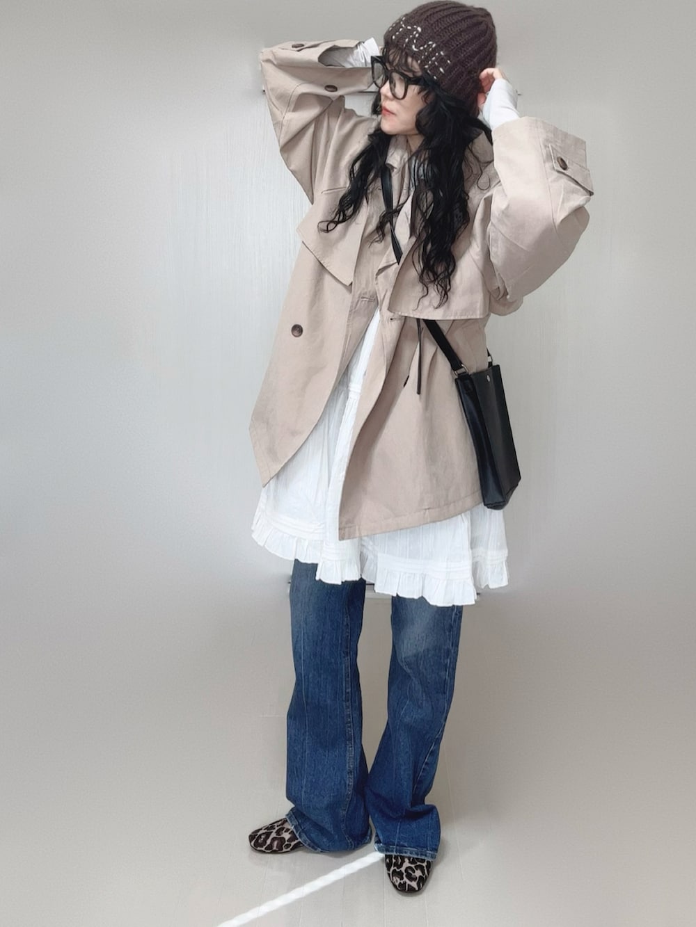 ベージュ系のトレンチコート、ホワイト系のワンピース、ブラック系のショルダーバッグを着用したレディースの春コーディネートの3枚目の写真