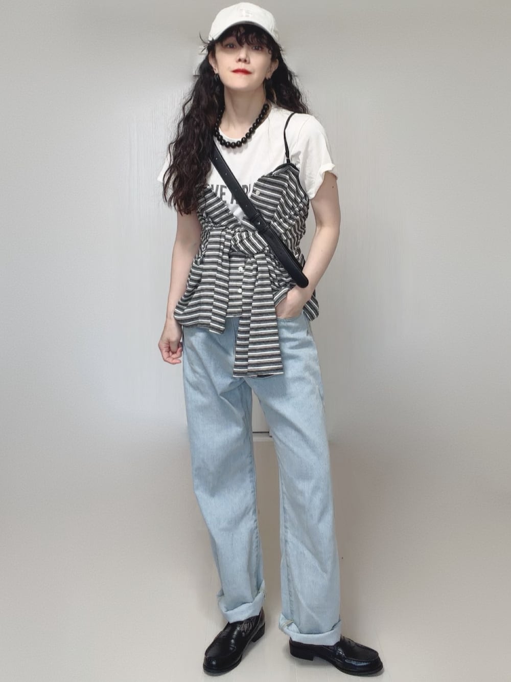 ホワイト系のTシャツ/カットソー、グレー系のカーディガン/ボレロ、ブルー系のデニムパンツを着用したレディースの春コーディネートの3枚目の写真