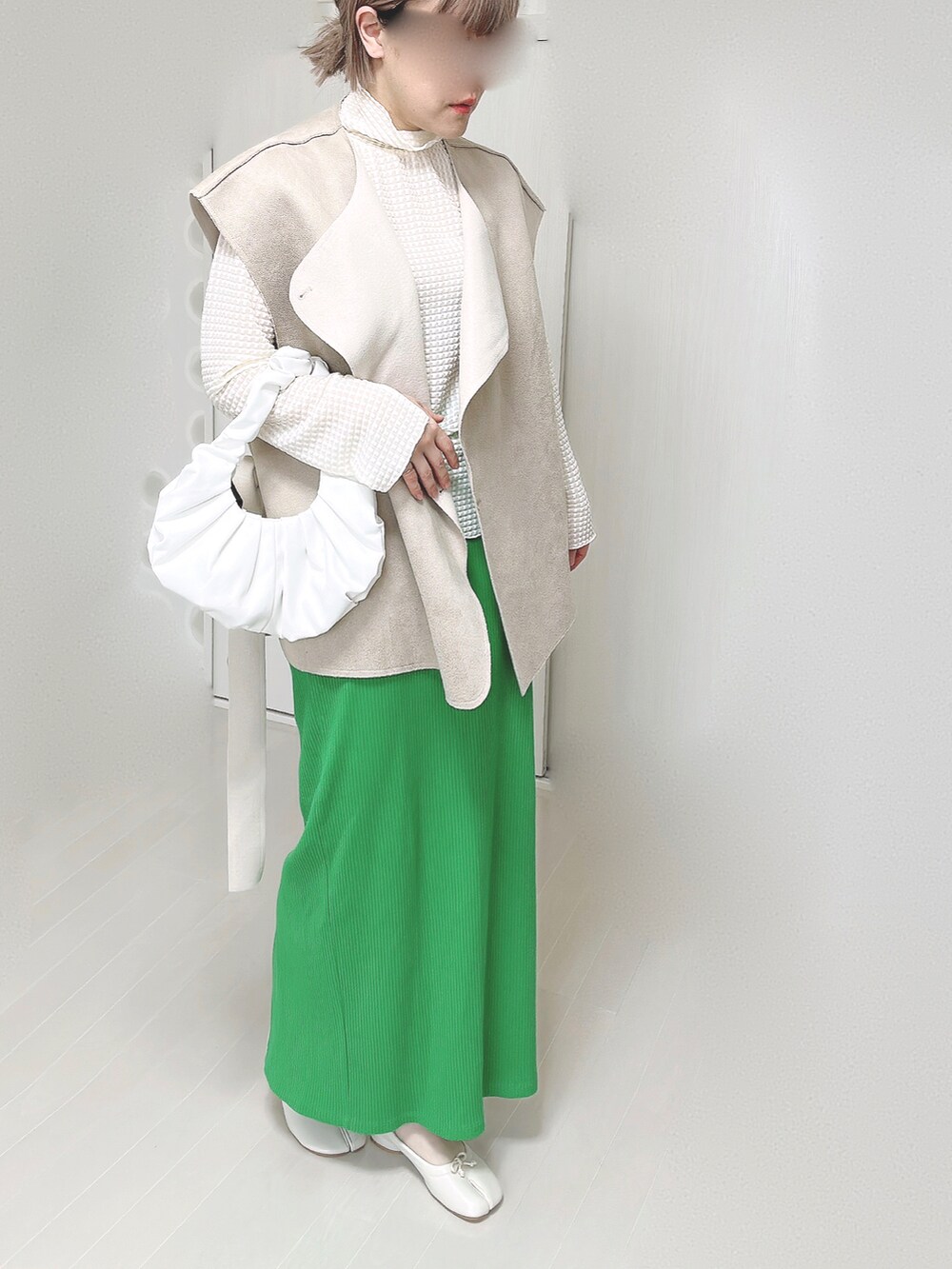 ホワイト系のTシャツ/カットソー、ベージュ系のベスト、グリーン系のスカートを着用したレディースの春コーディネートの4枚目の写真