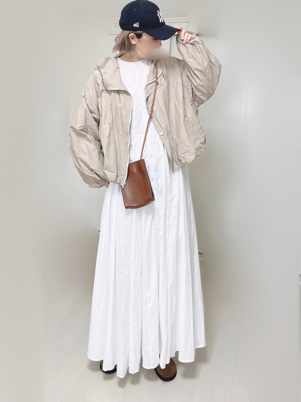 ベージュ系のマウンテンパーカー、ホワイト系のシャツワンピース、ブラウン系のショルダーバッグを着用したレディースの春コーディネートの5枚目の写真