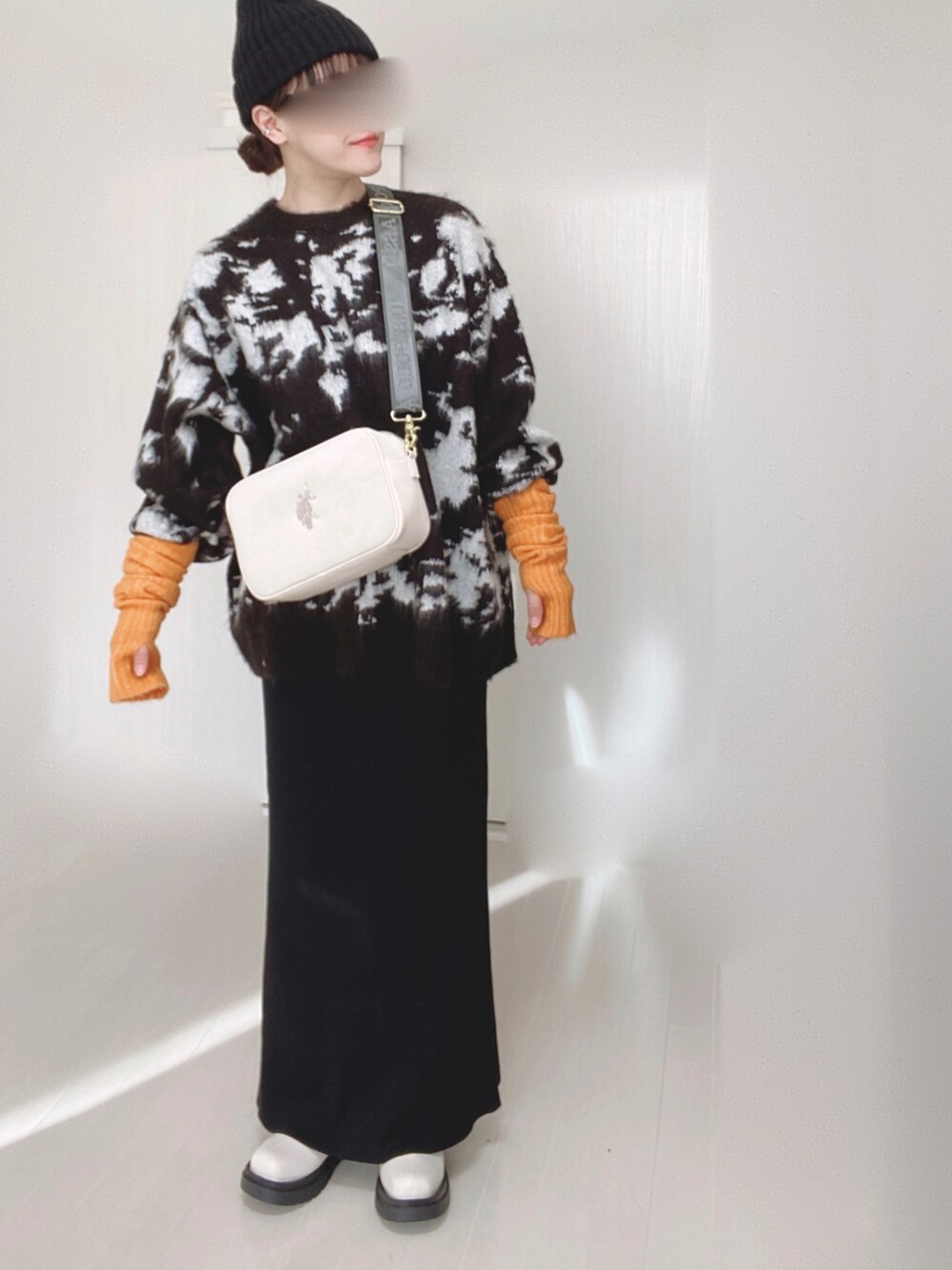 ホワイト系のショルダーバッグ、ブラック系のニット/セーター、ブラック系のスカートを着用したレディースの冬コーディネートの4枚目の写真
