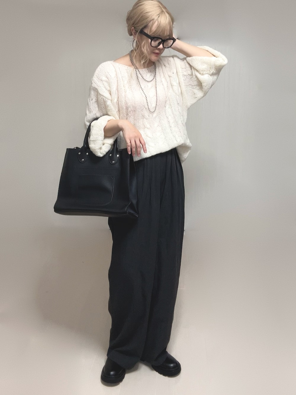 ホワイト系のニット/セーター、ブラック系のブーツ、ブラック系のトートバッグを着用したレディースの夏コーディネートの5枚目の写真