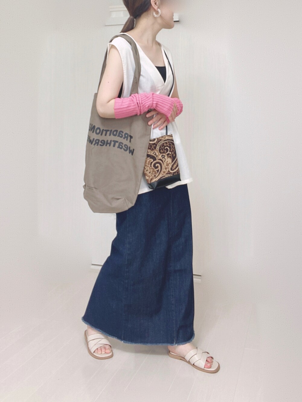 ブルー系のデニムスカート、ブラウン系のトートバッグ、ブラック系のショルダーバッグを着用したレディースの夏コーディネートの5枚目の写真