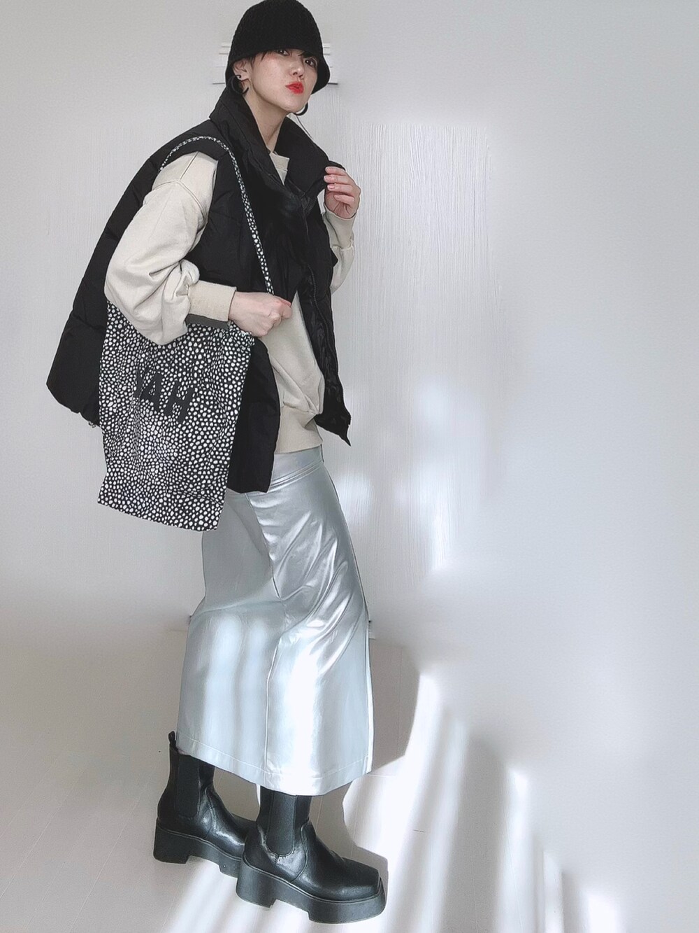 ベージュ系のスウェット、シルバー系のスカート、ブラック系のダウンベストを着用したレディースの冬コーディネートの3枚目の写真