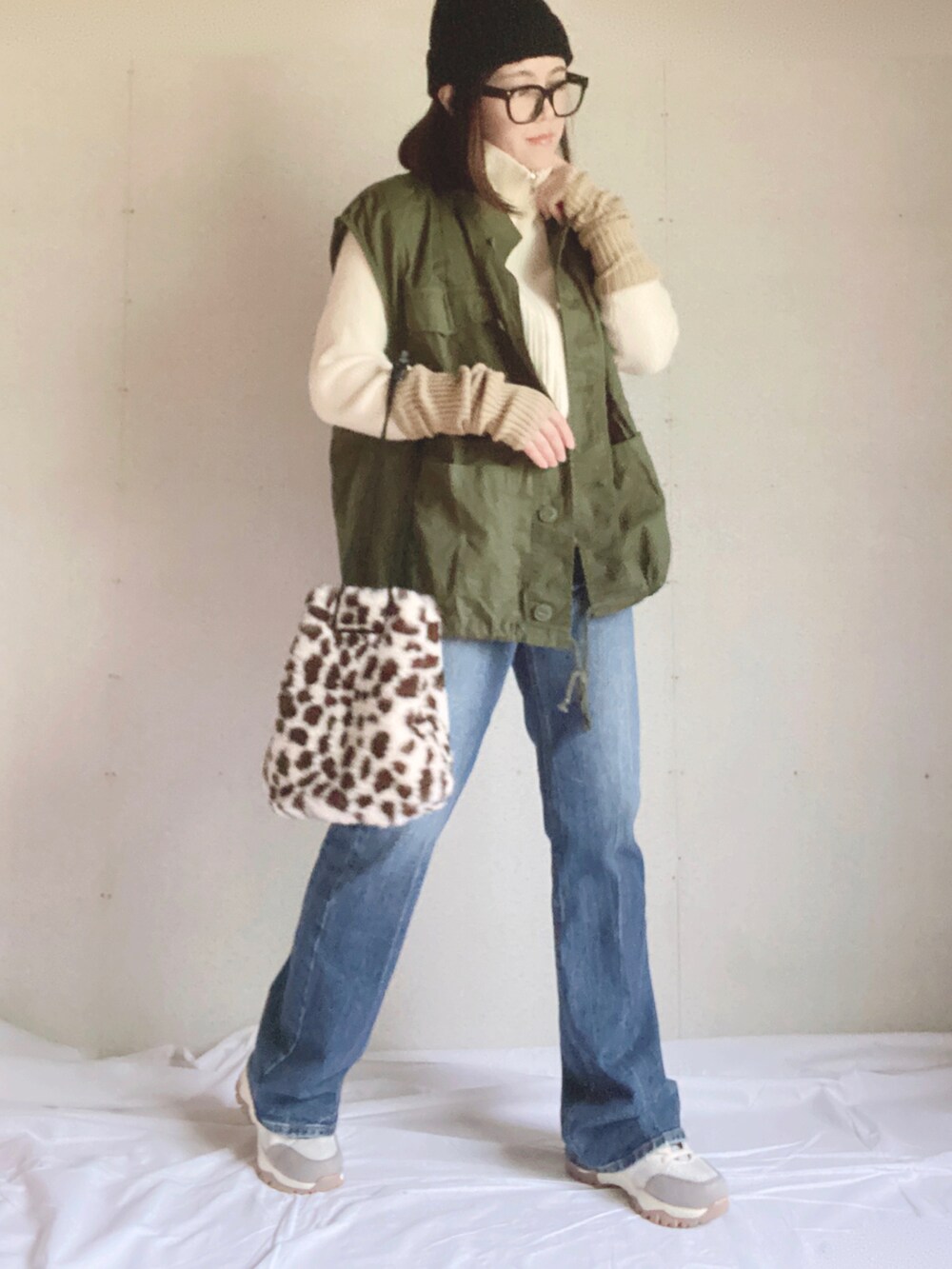 ブルー系のデニムパンツ、ベージュ系のスニーカー、ホワイト系のニット/セーターを着用したレディースの秋コーディネートの2枚目の写真