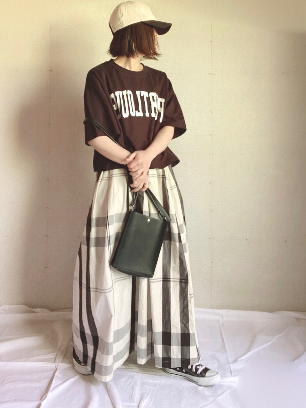 ホワイト系のスカート、ブラック系のTシャツ/カットソー、グリーン系のハンドバッグを着用したレディースの夏コーディネートの3枚目の写真