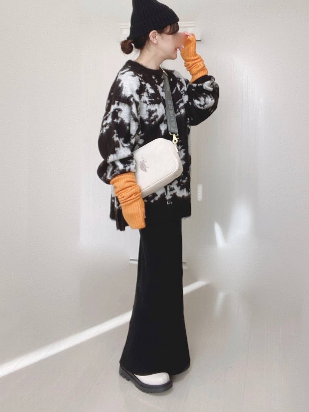 ホワイト系のショルダーバッグ、ブラック系のニット/セーター、ブラック系のスカートを着用したレディースの冬コーディネートの2枚目の写真