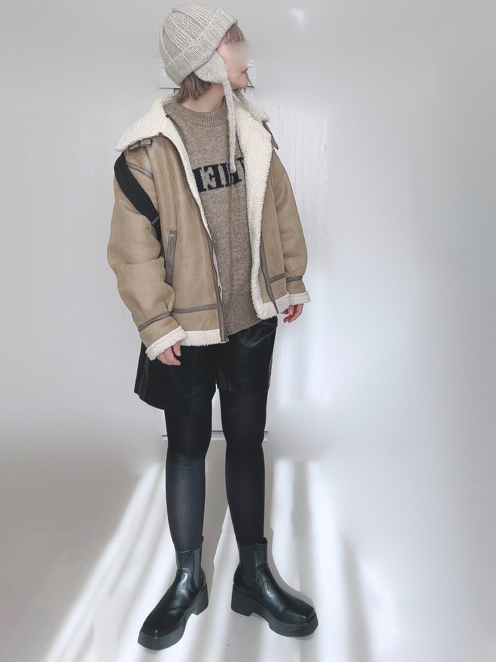 ベージュ系のムートンコート、ベージュ系のニット/セーター、ブラック系のバックパック/リュックを着用したレディースの冬コーディネートの3枚目の写真