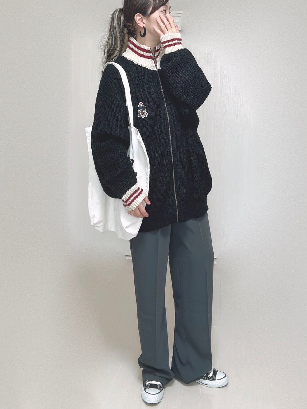 ブラック系のニット/セーター、ホワイト系のトートバッグ、グレー系のスラックスを着用したレディースの秋コーディネートの4枚目の写真