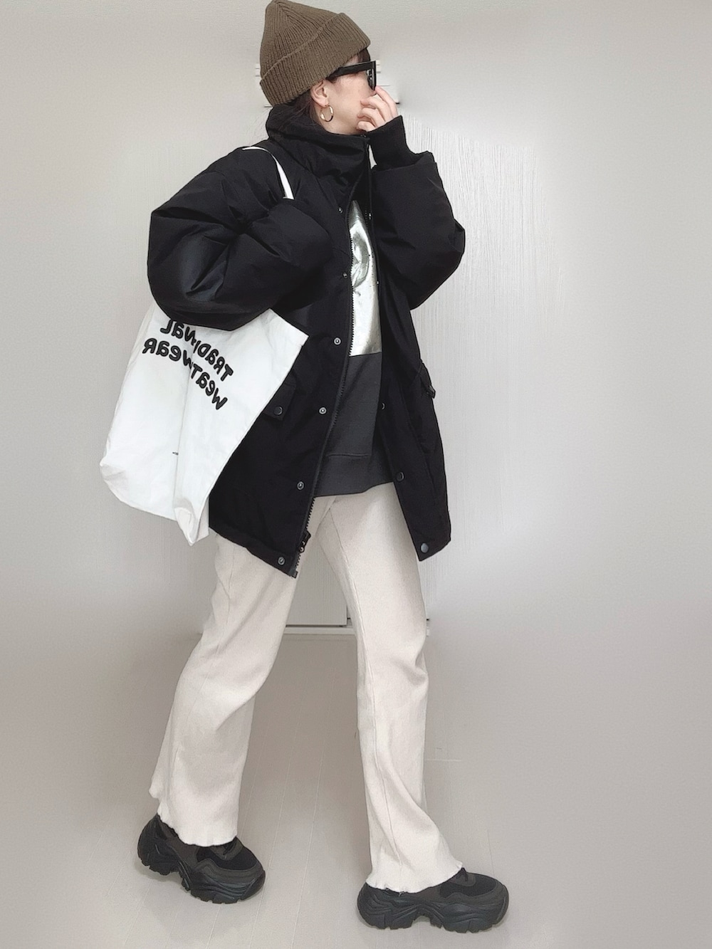 ブラック系のブルゾン、ブラック系のスウェット、ホワイト系のトートバッグを着用したレディースの冬コーディネートの2枚目の写真