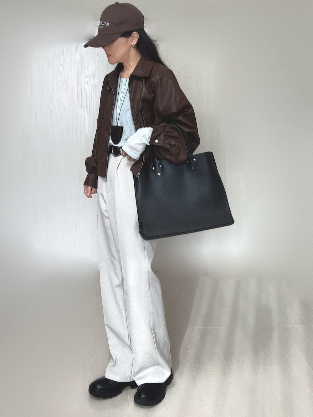 ブルー系のTシャツ/カットソー、ブラウン系のブルゾン、ブラック系のトートバッグを着用したレディースの冬コーディネートの2枚目の写真