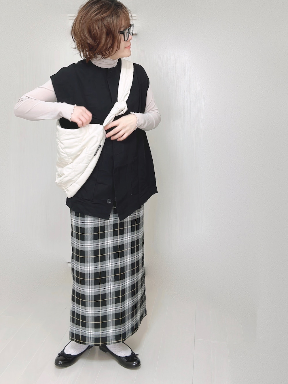 ブラック系のベスト、グレー系のTシャツ/カットソー、ホワイト系のショルダーバッグを着用したレディースの春コーディネートの3枚目の写真