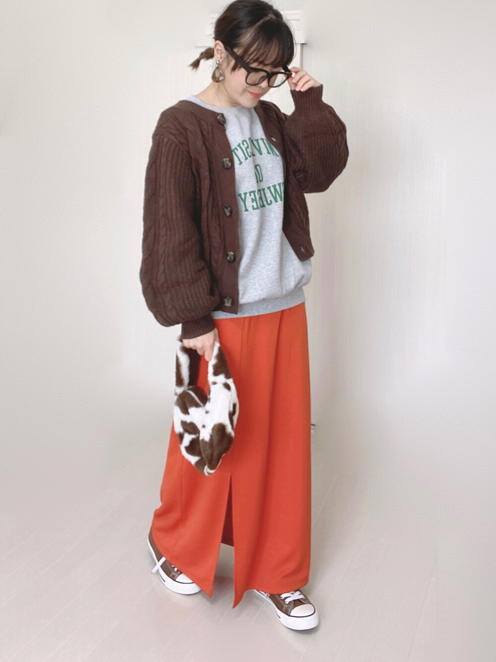 グレー系のスウェット、オレンジ系のスカート、ブラウン系のニット/セーターを着用したレディースの秋コーディネートの2枚目の写真