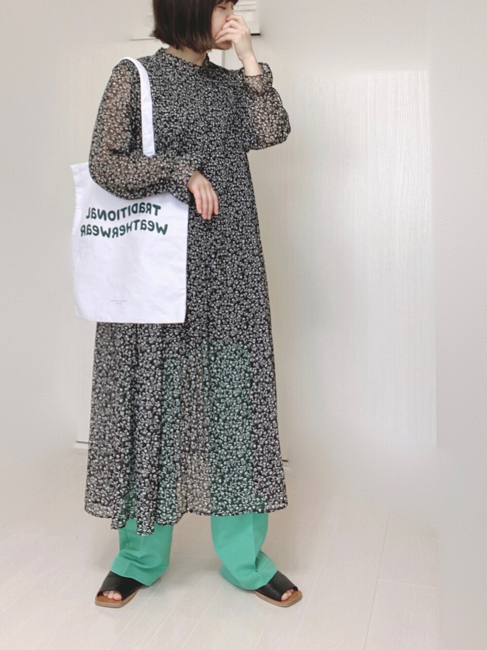 ホワイト系のトートバッグ、ブラック系のワンピース、グリーン系のスラックスを着用したレディースの春コーディネートの3枚目の写真
