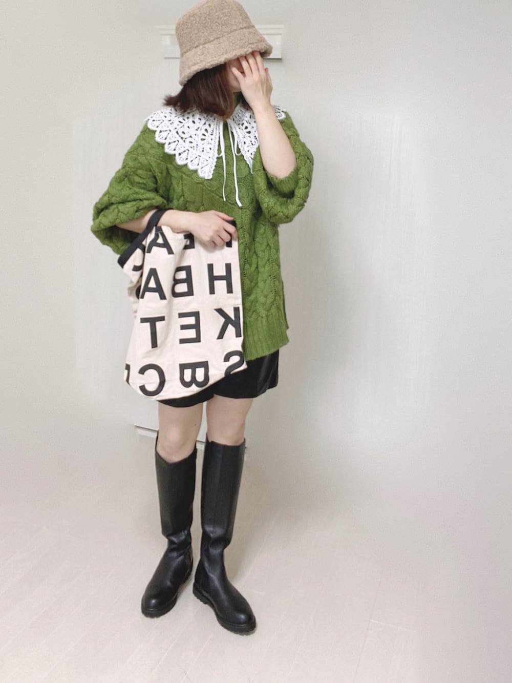 ブラック系のブーツ、グリーン系のニット/セーター、ホワイト系のトートバッグを着用したレディースの秋コーディネートの3枚目の写真