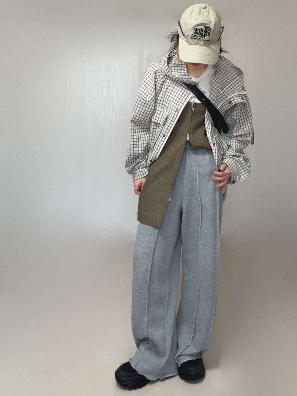ホワイト系のパーカー、グレー系のスウェットパンツ、ブラウン系のベストを着用したレディースの春コーディネートの2枚目の写真