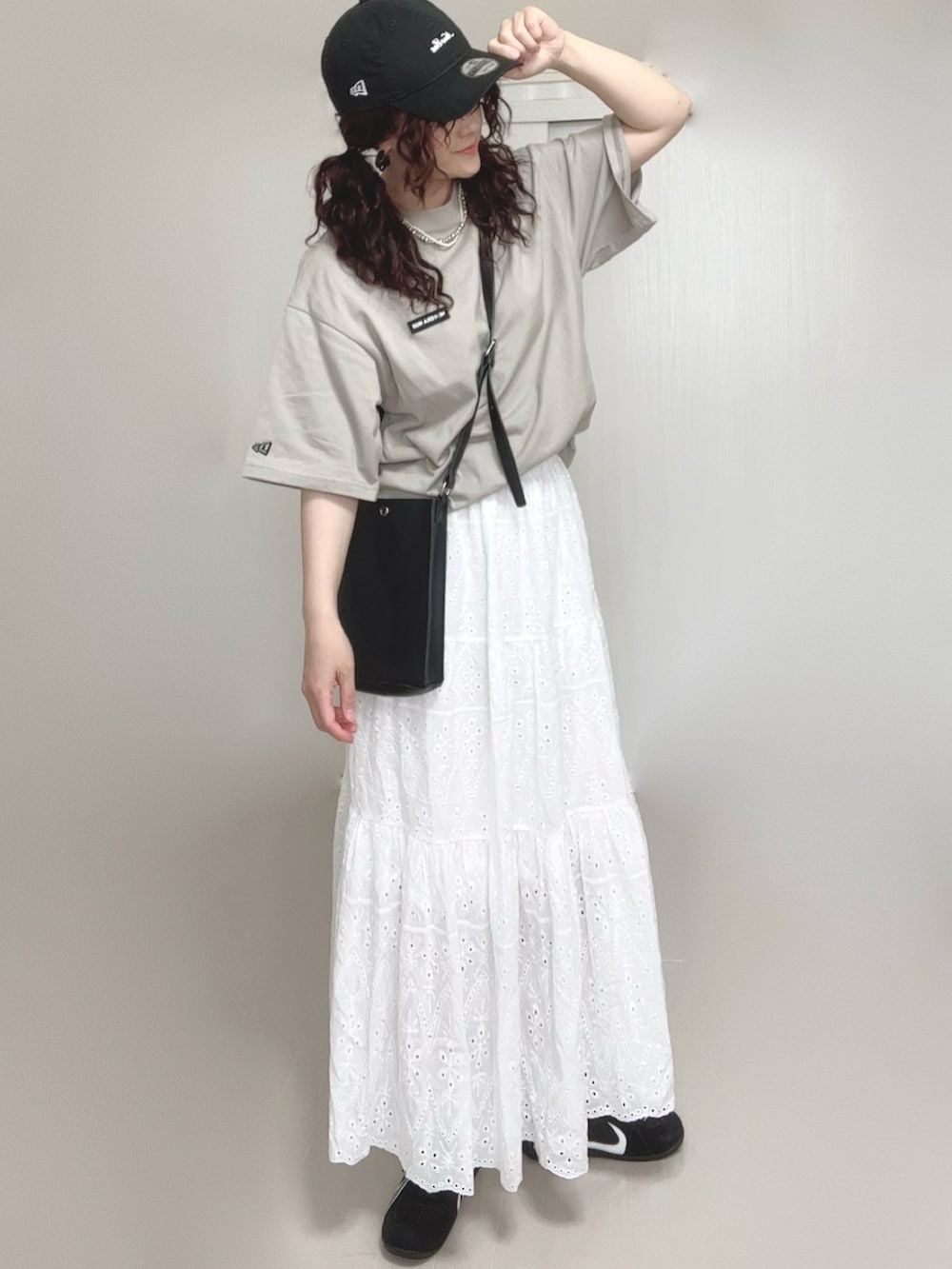 ブラック系のショルダーバッグ、ベージュ系のTシャツ/カットソー、ホワイト系のスカートを着用したレディースの夏コーディネートの4枚目の写真