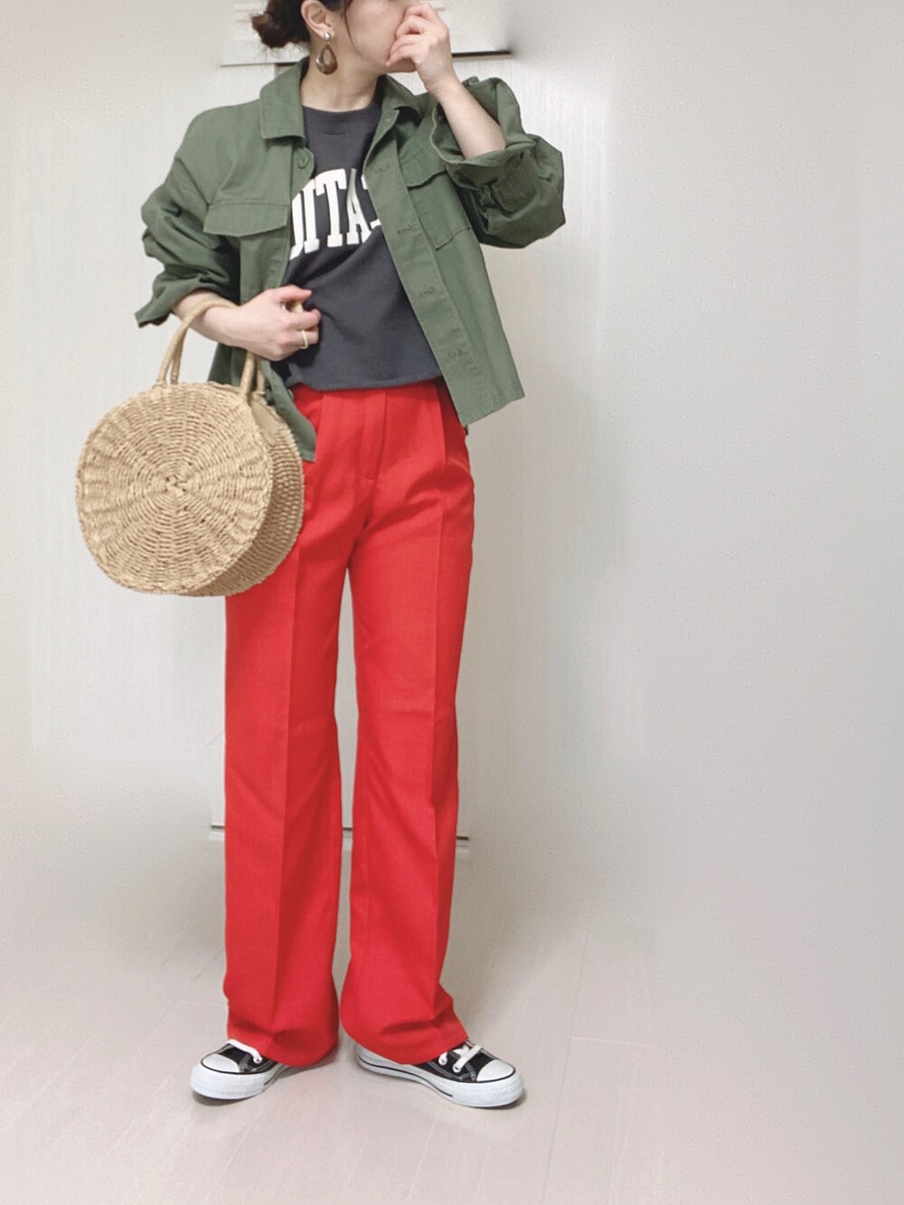 ベージュ系のかごバッグ、グリーン系のミリタリージャケット、ブラック系のスニーカーを着用したレディースの春コーディネートの2枚目の写真
