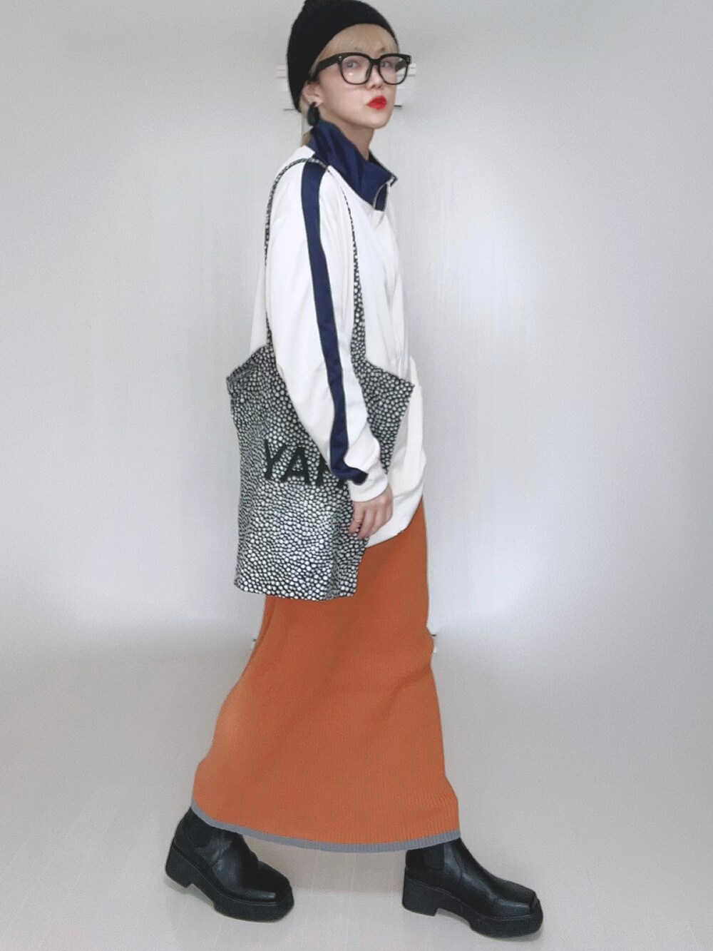 ベージュ系のジャージ、オレンジ系のスカート、ブラック系のブーツを着用したレディースの冬コーディネートの4枚目の写真