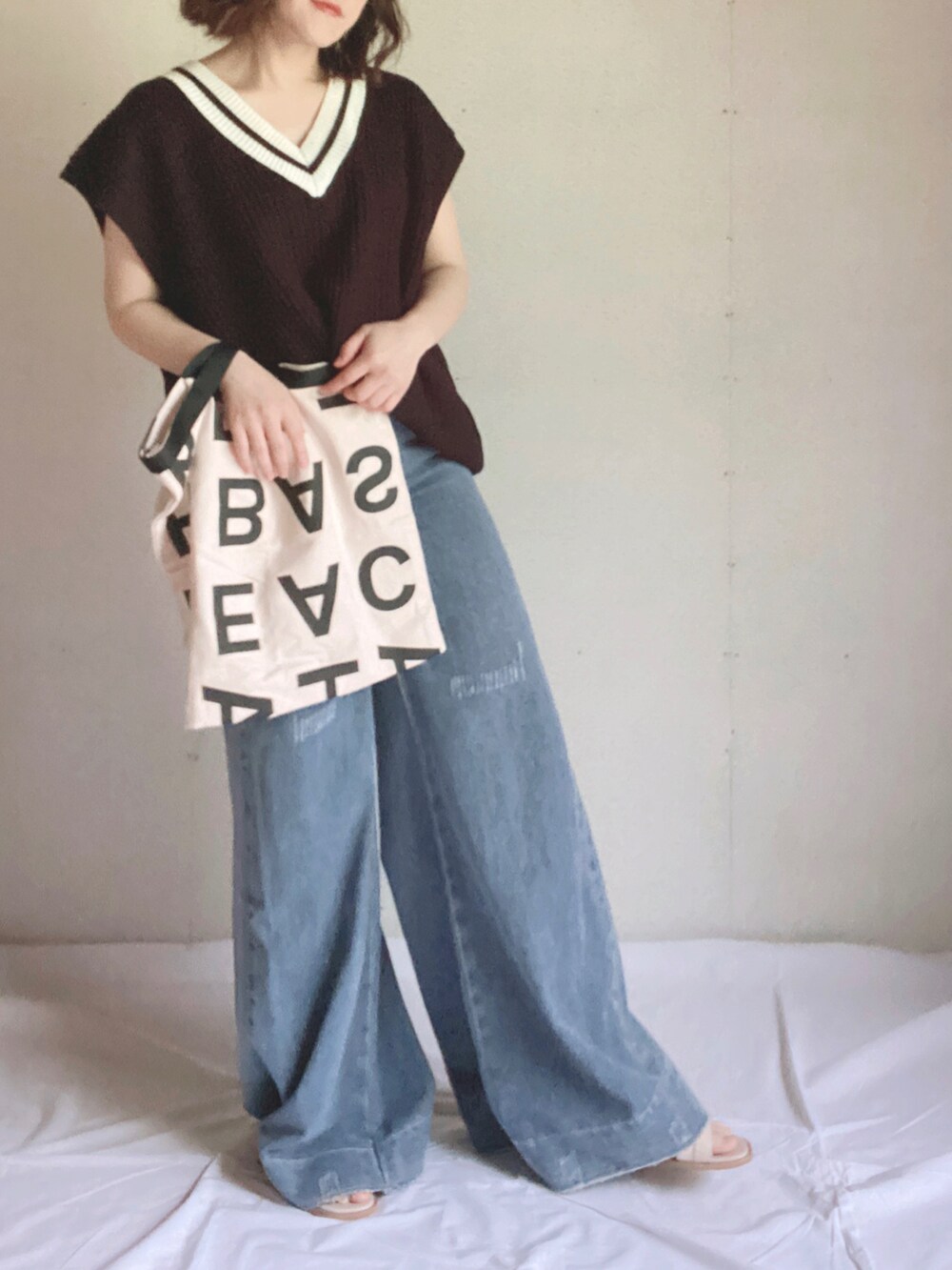 ブラック系のベスト、ホワイト系のトートバッグ、ホワイト系のサンダルを着用したレディースの夏コーディネートの5枚目の写真