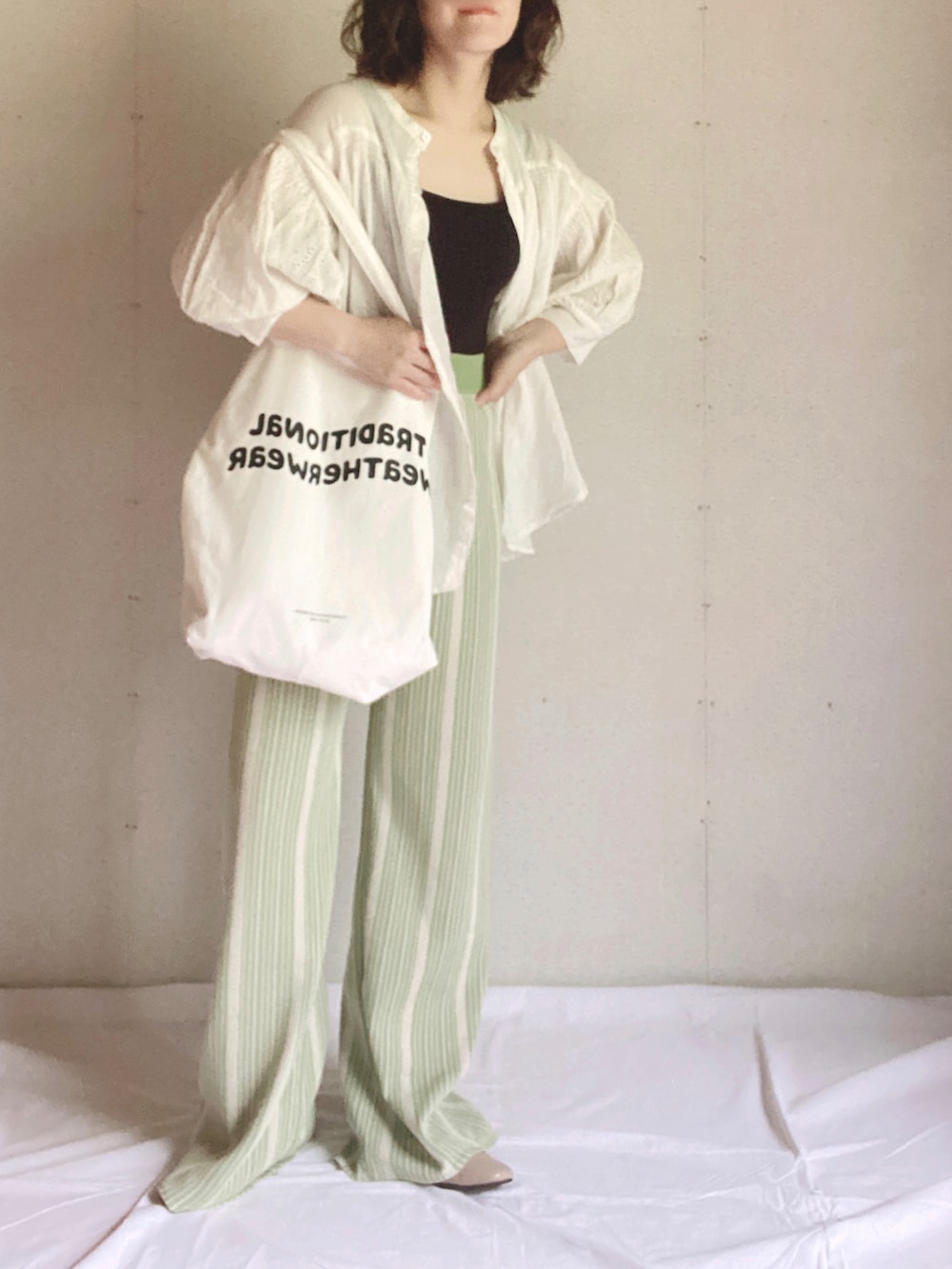 ホワイト系のシャツ/ブラウス、ホワイト系のトートバッグ、ベージュ系のパンプスを着用したレディースの夏コーディネートの3枚目の写真