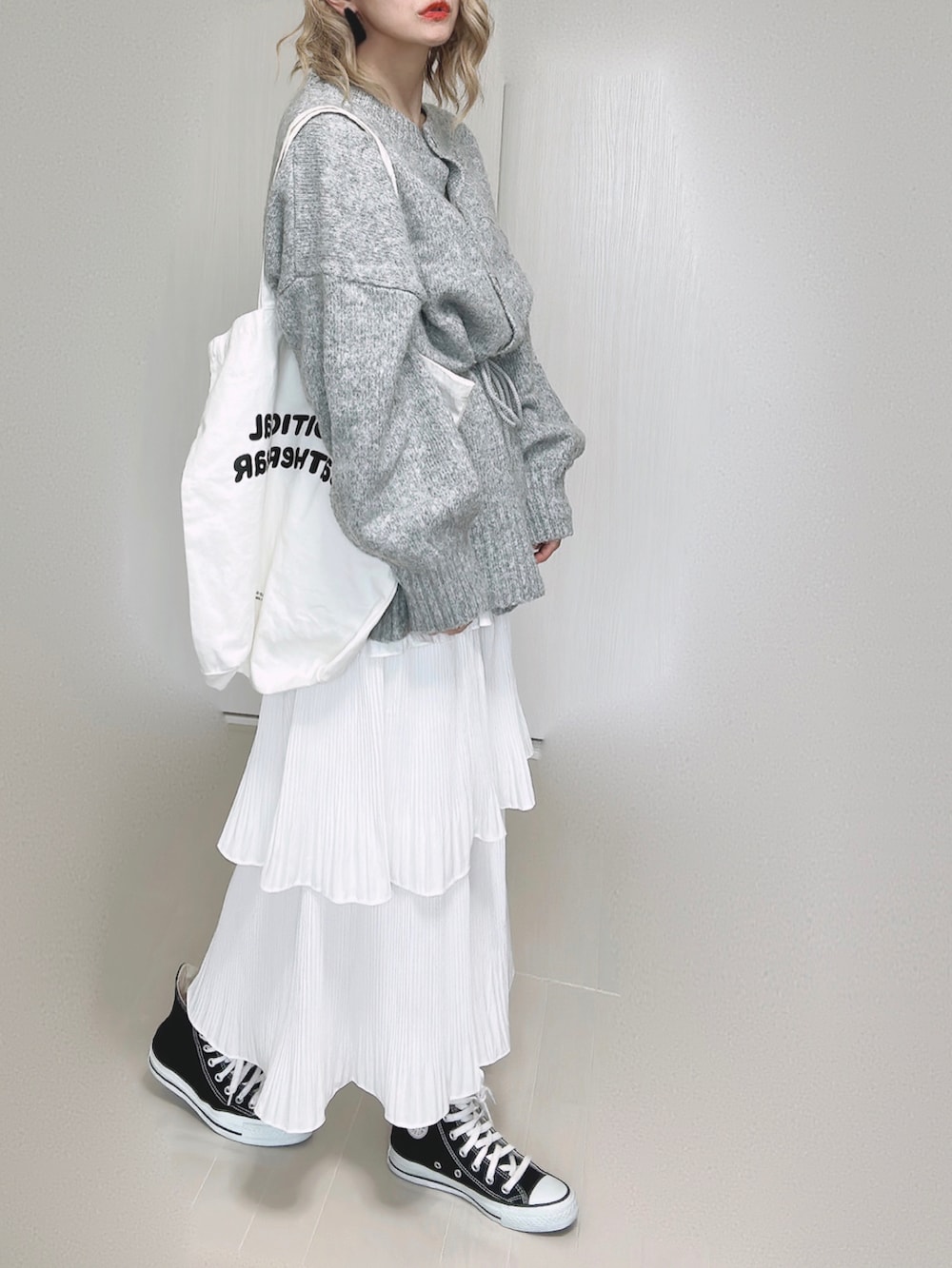 ホワイト系のスカート、ホワイト系のトートバッグ、ブラック系のスニーカーを着用したレディースの秋コーディネートの2枚目の写真